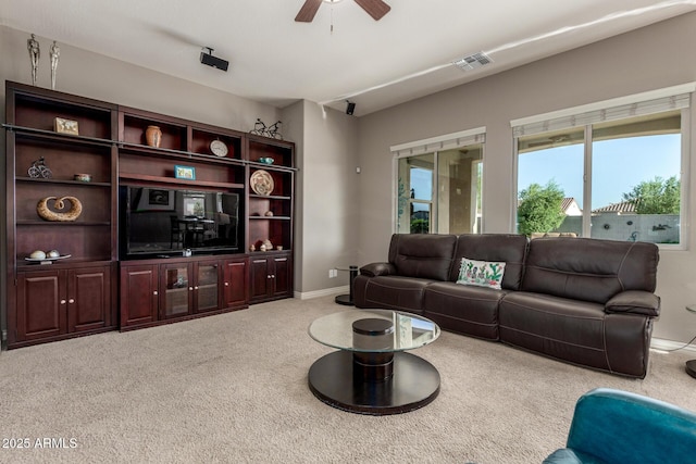 carpeted living area with a ceiling fan and baseboards