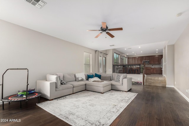 living room featuring dark wood-type flooring and ceiling fan