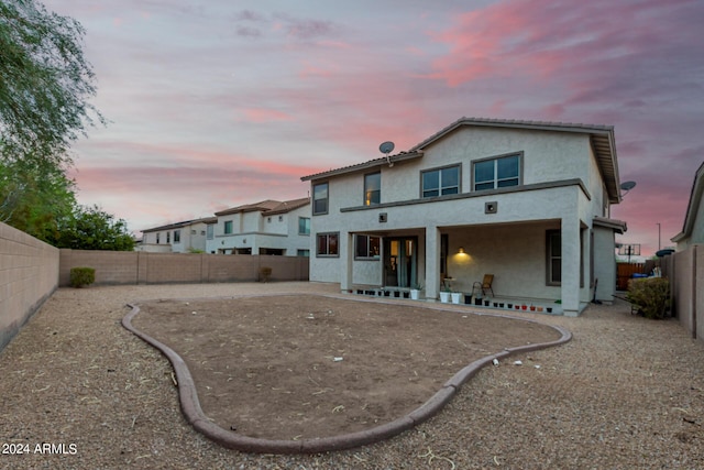 back house at dusk featuring a patio area