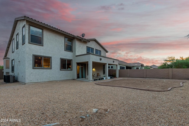 back house at dusk with central AC and a patio area