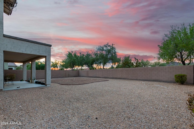 yard at dusk featuring a patio