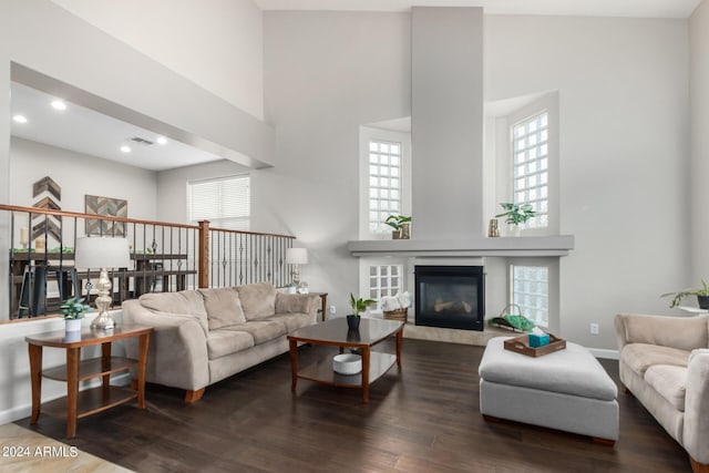 living room with dark wood-type flooring, a fireplace, and a high ceiling