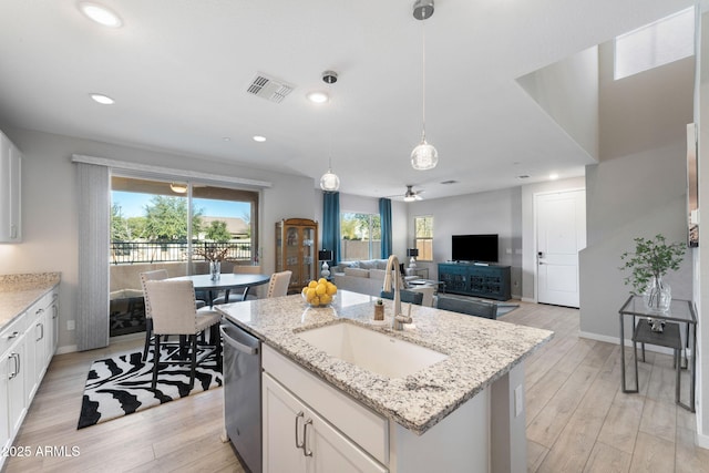 kitchen with a kitchen island with sink, sink, stainless steel dishwasher, and white cabinets