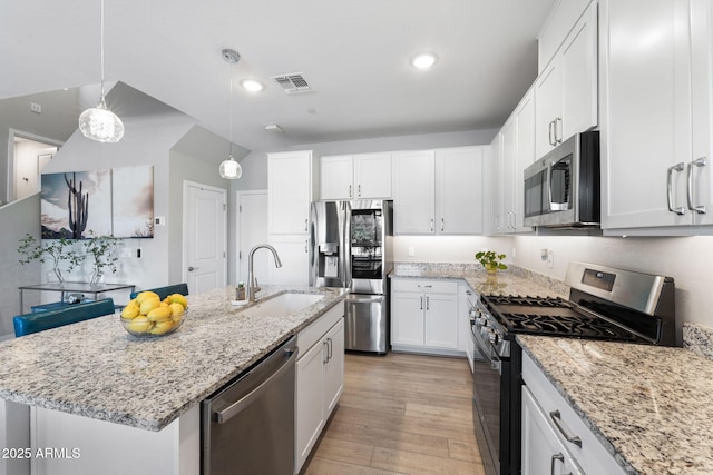 kitchen with sink, a kitchen island with sink, hanging light fixtures, stainless steel appliances, and white cabinets