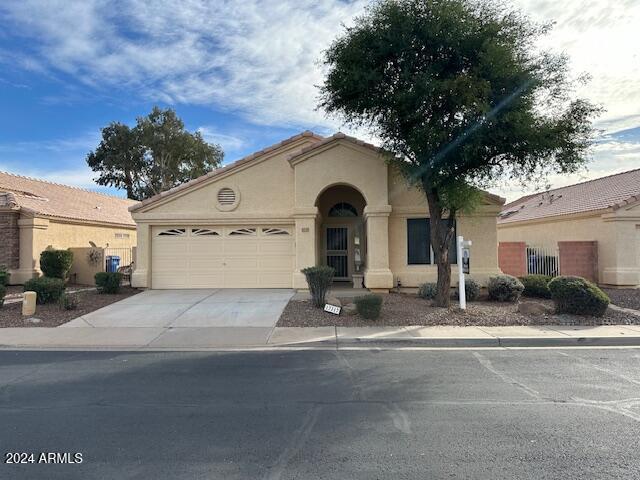 mediterranean / spanish house with stucco siding, an attached garage, a tile roof, and driveway