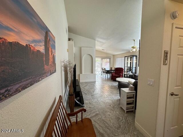 corridor featuring baseboards and lofted ceiling