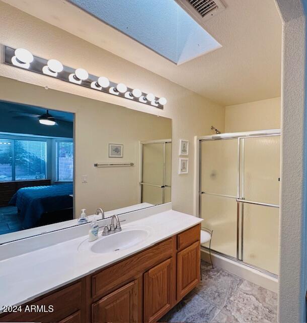 bathroom with tile patterned flooring, vanity, walk in shower, and a skylight