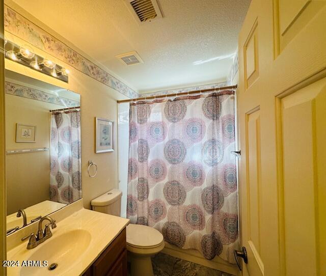 full bathroom with shower / tub combo, vanity, a textured ceiling, and toilet