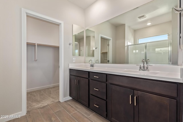 bathroom featuring a shower with door and vanity