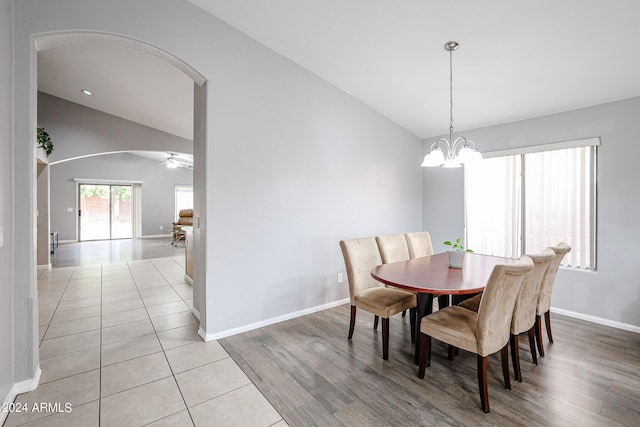 dining area featuring ceiling fan with notable chandelier, light hardwood / wood-style floors, and vaulted ceiling