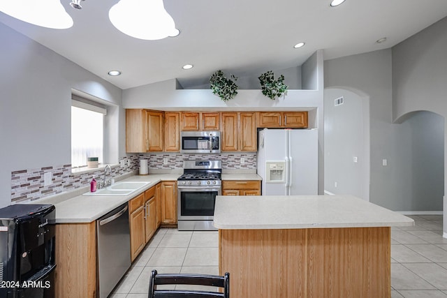 kitchen featuring sink, vaulted ceiling, appliances with stainless steel finishes, tasteful backsplash, and a kitchen island