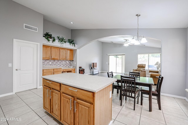 kitchen featuring backsplash, light tile patterned floors, decorative light fixtures, a center island, and lofted ceiling