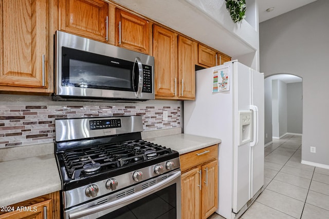 kitchen featuring backsplash, light tile patterned floors, and stainless steel appliances