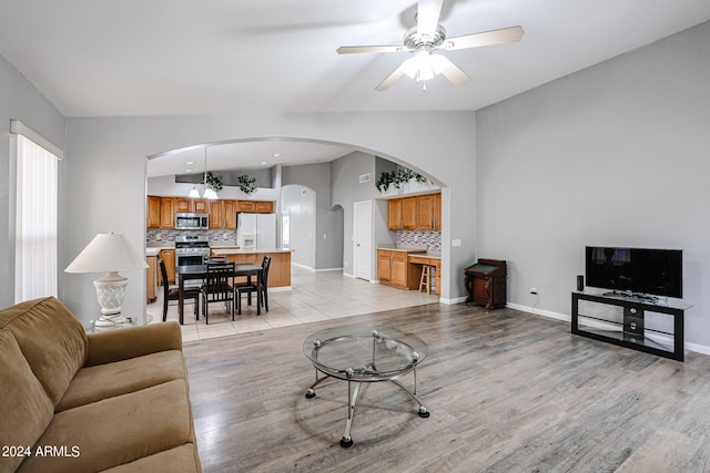 living room with ceiling fan, lofted ceiling, and light wood-type flooring