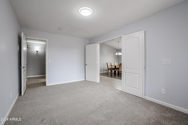 unfurnished bedroom with light carpet and a notable chandelier