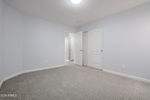 unfurnished bedroom featuring light colored carpet and a closet