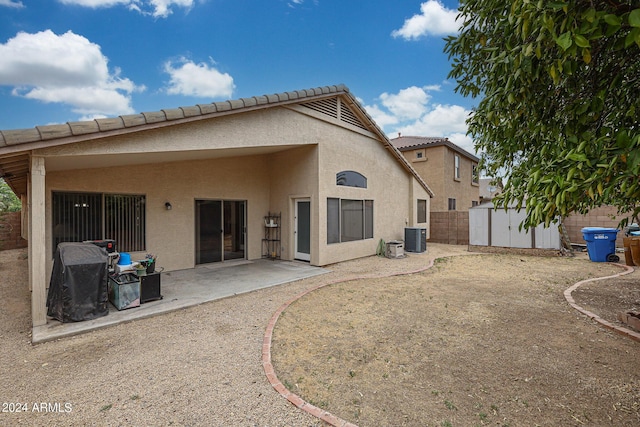 rear view of property featuring a storage unit, central air condition unit, and a patio