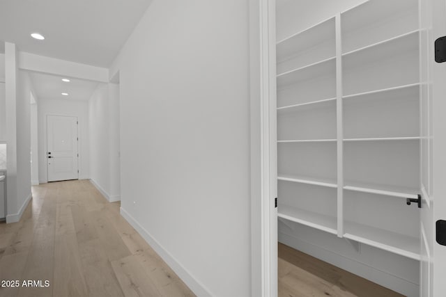 hallway featuring light wood finished floors, recessed lighting, and baseboards