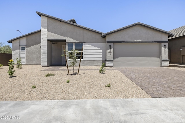 view of front of house featuring a garage, decorative driveway, and stucco siding