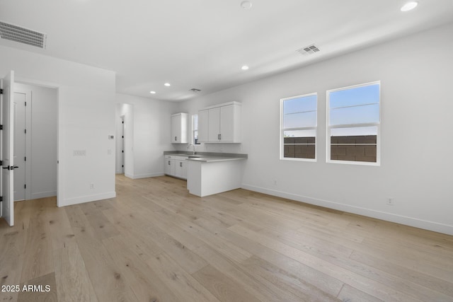 kitchen with light wood-type flooring, white cabinetry, and visible vents