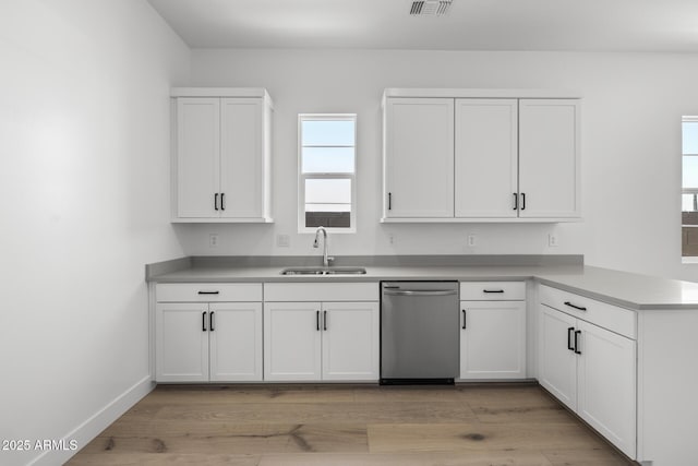 kitchen featuring dishwasher, light countertops, a sink, and white cabinets