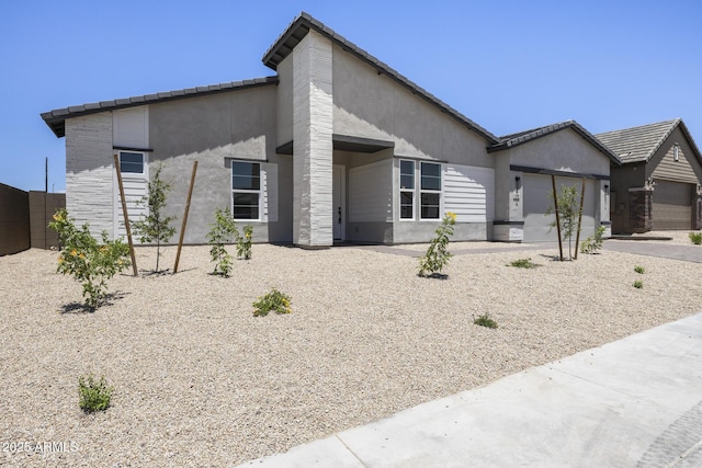 view of front of home featuring an attached garage, fence, and stucco siding