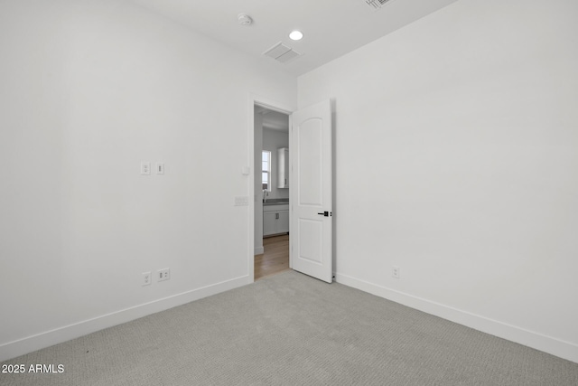 spare room featuring recessed lighting, light colored carpet, visible vents, and baseboards