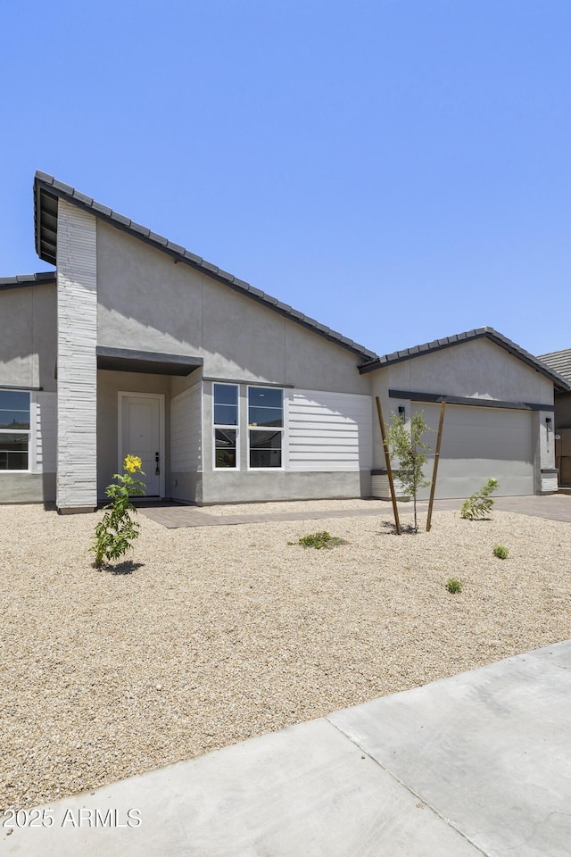 view of front of house featuring a garage, concrete driveway, and stucco siding