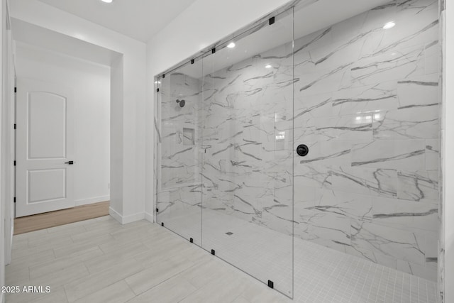 bathroom featuring baseboards and a marble finish shower