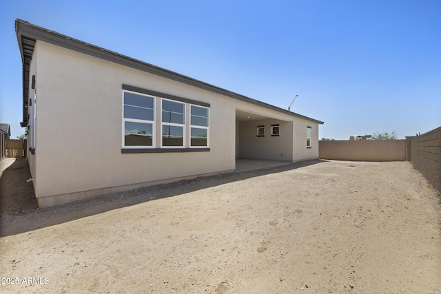 back of property with a fenced backyard and stucco siding