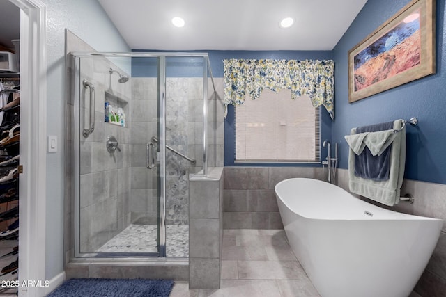 full bathroom featuring a spacious closet, recessed lighting, a shower stall, and a freestanding tub