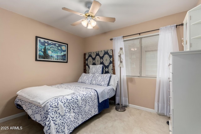 bedroom featuring light carpet, a ceiling fan, and baseboards