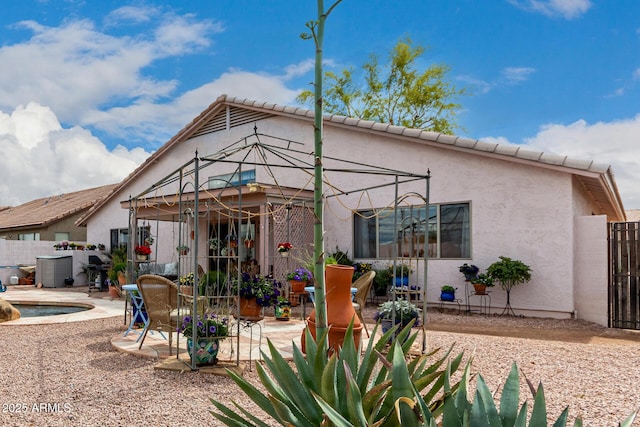 rear view of house with stucco siding, a swimming pool, fence, a gazebo, and a patio area