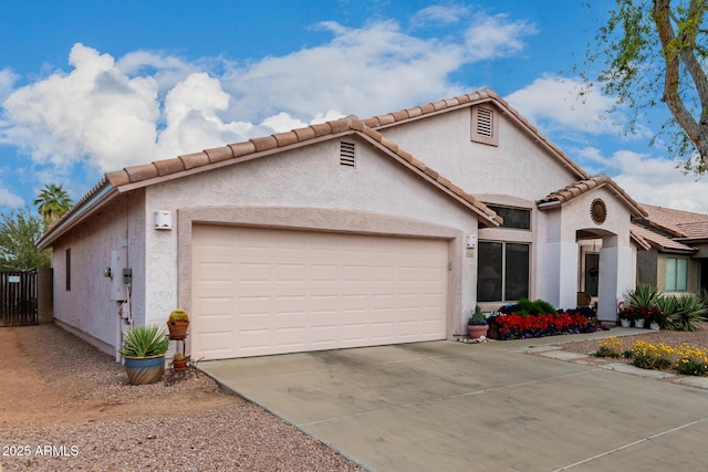 mediterranean / spanish house featuring stucco siding, a tiled roof, concrete driveway, and a garage