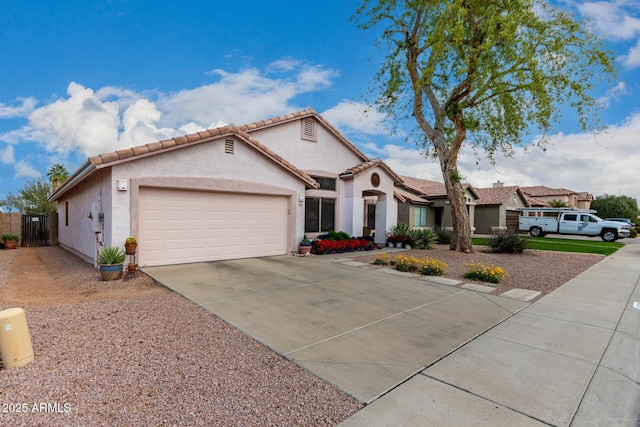 mediterranean / spanish-style house featuring stucco siding, a tile roof, fence, concrete driveway, and a garage