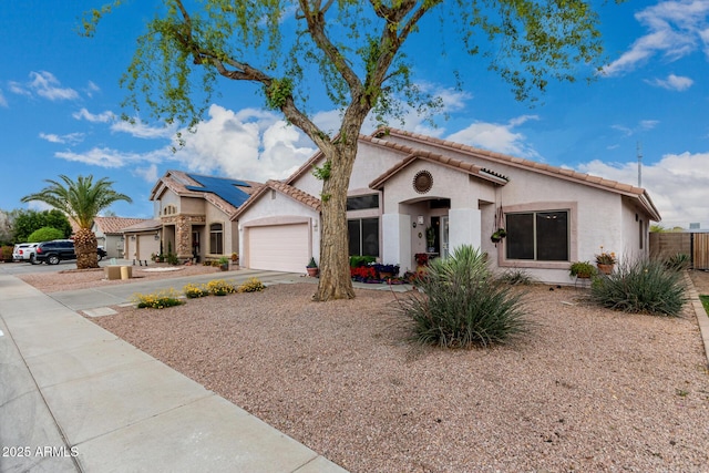 mediterranean / spanish house with concrete driveway, an attached garage, a tile roof, and stucco siding