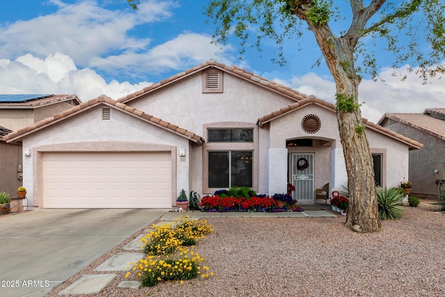 mediterranean / spanish-style home featuring a tiled roof, stucco siding, an attached garage, and driveway