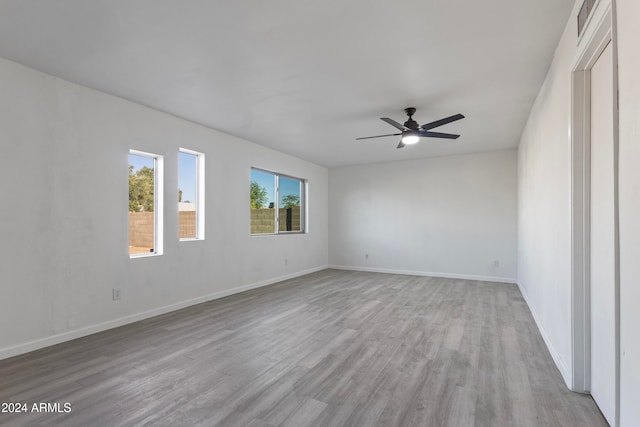 empty room with ceiling fan and light hardwood / wood-style flooring