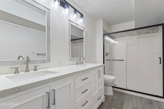 bathroom with hardwood / wood-style floors, vanity, toilet, and a shower with shower door