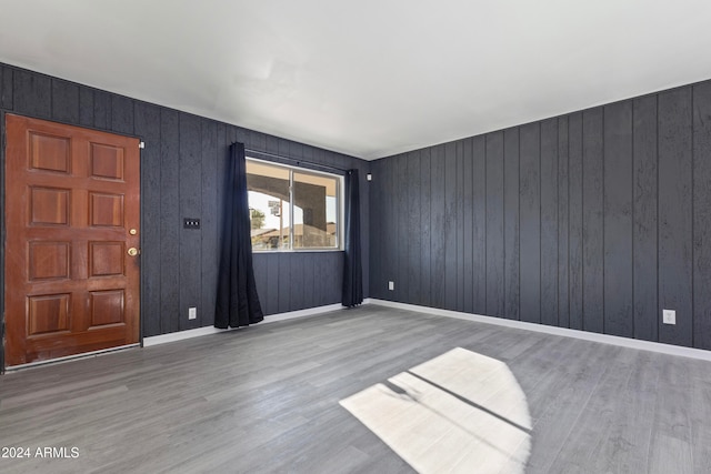 empty room featuring wood walls and hardwood / wood-style floors