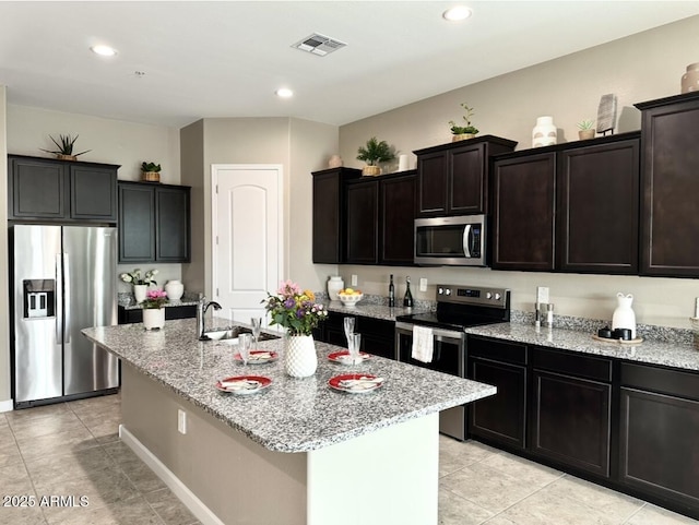 1255 N Arizona Ave Unit 1235, Chandler, AZ 85225 - kitchen featuring appliances with stainless steel finishes, light stone countertops, light tile patterned floors, an island with sink, and recessed lighting