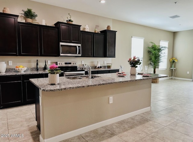 1255 N Arizona Ave Unit 1235, Chandler, AZ 85225 - kitchen featuring stainless steel appliances, light tile patterned floors, a center island with sink, light stone countertops, and recessed lighting