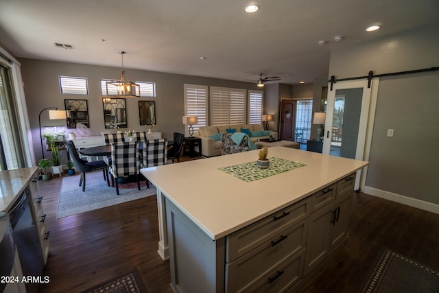 kitchen featuring a barn door, gray cabinetry, pendant lighting, and dark wood-type flooring