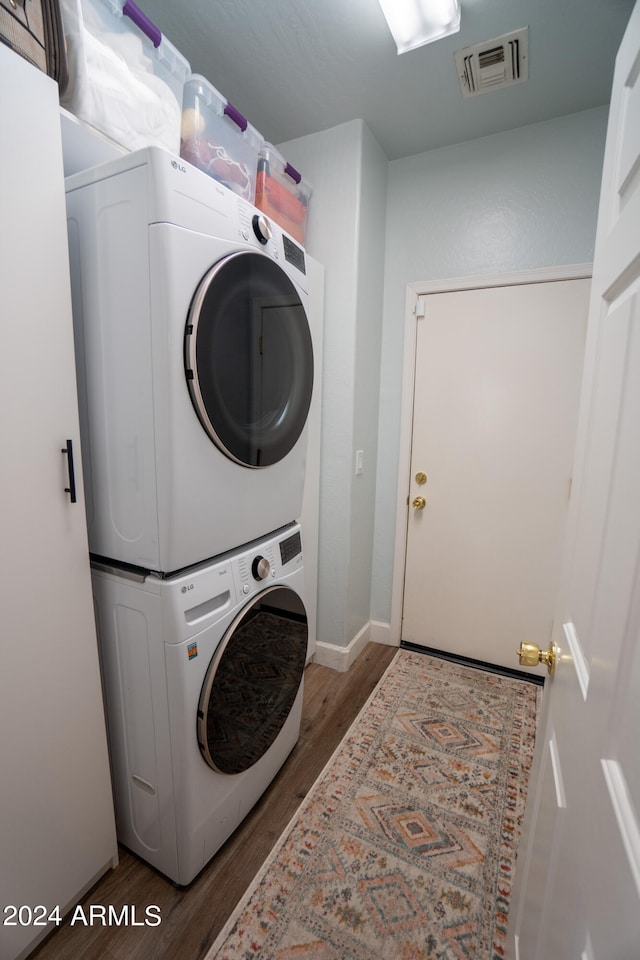 laundry room featuring dark hardwood / wood-style floors and stacked washer and clothes dryer