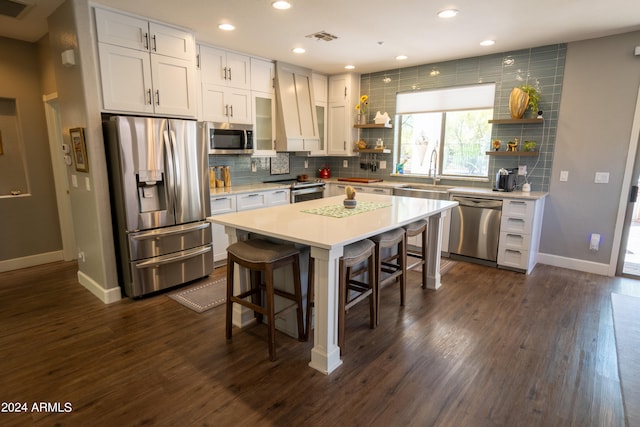 kitchen featuring premium range hood, dark hardwood / wood-style flooring, white cabinets, a kitchen bar, and appliances with stainless steel finishes