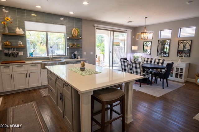 kitchen with a center island, dark wood-type flooring, backsplash, pendant lighting, and sink