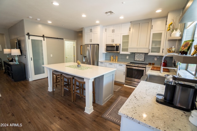 kitchen featuring a barn door, backsplash, a kitchen island, and stainless steel appliances