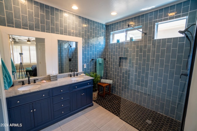 bathroom featuring ceiling fan, tile flooring, tiled shower, and double sink vanity