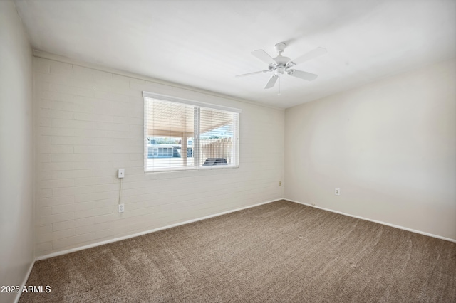 carpeted spare room featuring brick wall and ceiling fan