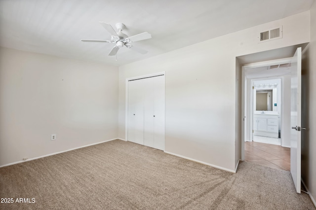 unfurnished bedroom featuring light colored carpet, a closet, and ceiling fan